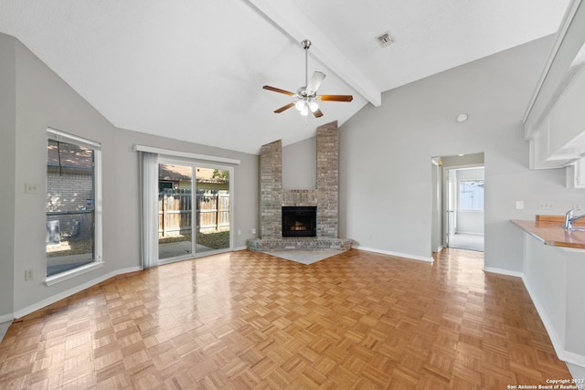 unfurnished living room featuring beam ceiling, light parquet floors, ceiling fan, and a brick fireplace