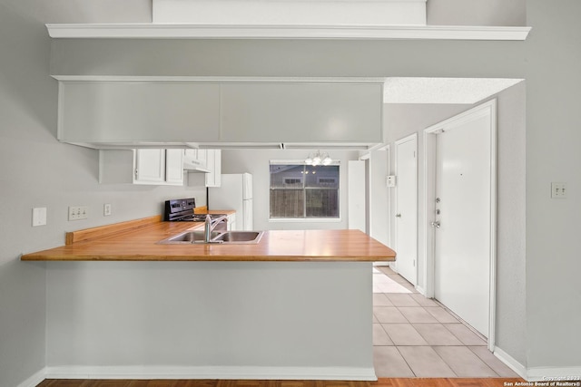 kitchen featuring white cabinets, white refrigerator, sink, light tile patterned flooring, and kitchen peninsula