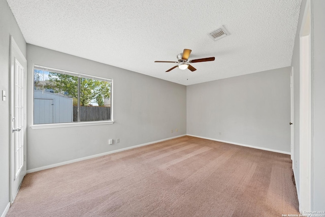 spare room with a textured ceiling, ceiling fan, and light carpet