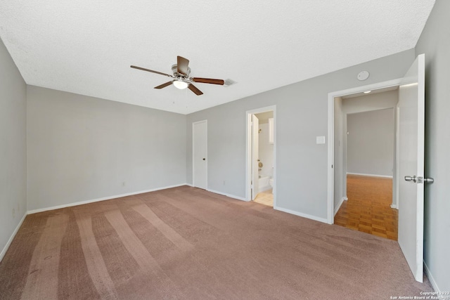 unfurnished bedroom featuring a textured ceiling, connected bathroom, light colored carpet, and ceiling fan