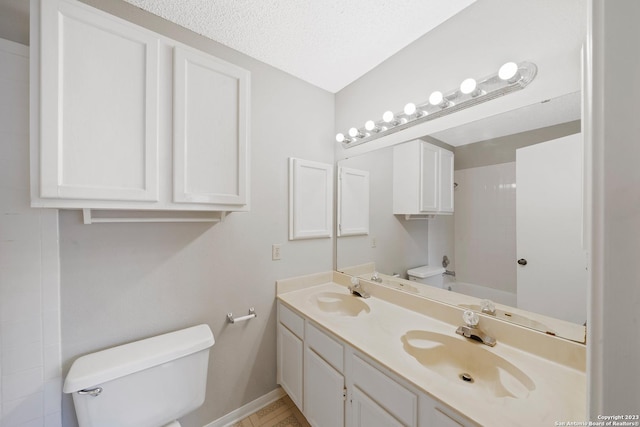 full bathroom with vanity, a textured ceiling, toilet, and washtub / shower combination