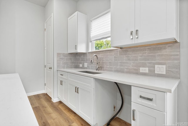 kitchen featuring decorative backsplash, light hardwood / wood-style flooring, white cabinetry, and sink