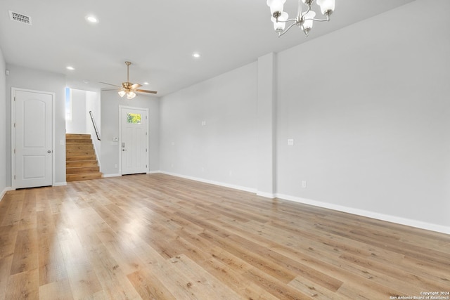 unfurnished room featuring ceiling fan with notable chandelier and light hardwood / wood-style flooring