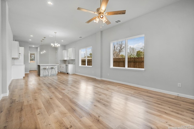 unfurnished living room featuring ceiling fan with notable chandelier, light wood-type flooring, and sink