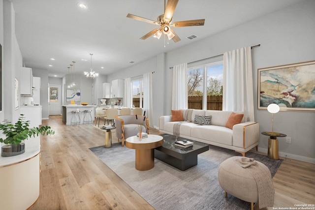 living room featuring light hardwood / wood-style floors and ceiling fan with notable chandelier