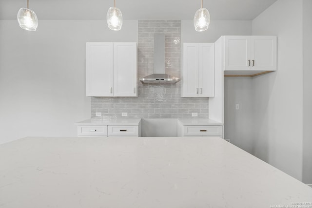 kitchen featuring white cabinets, wall chimney exhaust hood, and decorative light fixtures