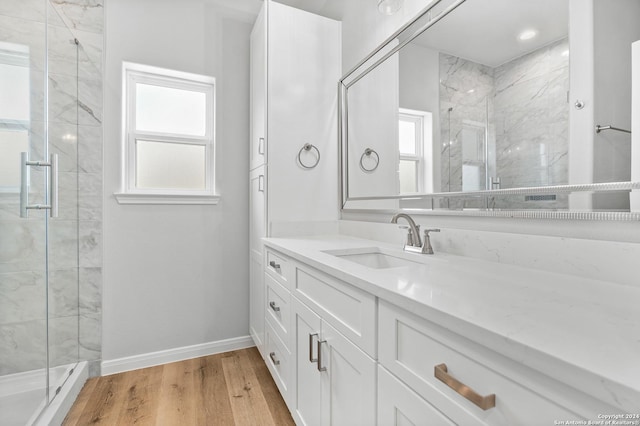 bathroom with wood-type flooring, vanity, and a shower with door