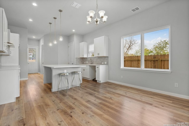 kitchen featuring a chandelier, a center island, white cabinetry, and hanging light fixtures