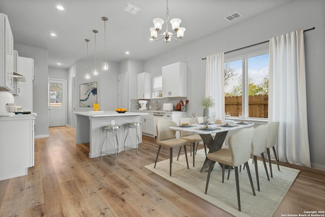 dining space with light wood-type flooring and an inviting chandelier