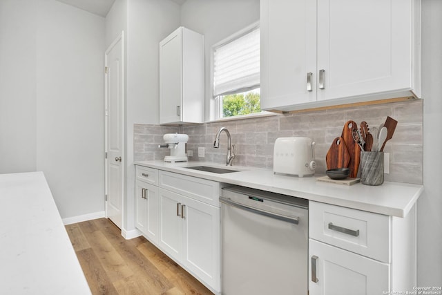 kitchen featuring sink, tasteful backsplash, stainless steel dishwasher, white cabinets, and light wood-type flooring