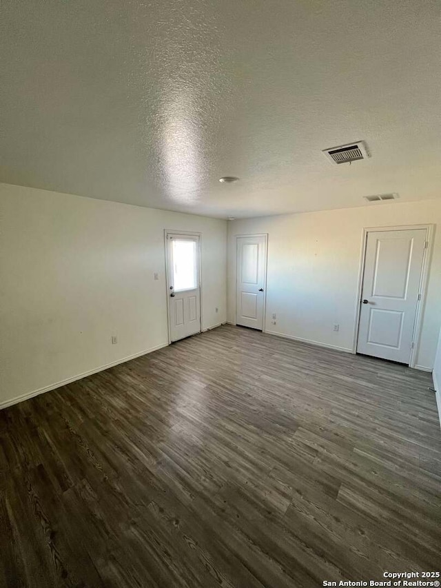 spare room featuring a textured ceiling and dark hardwood / wood-style floors