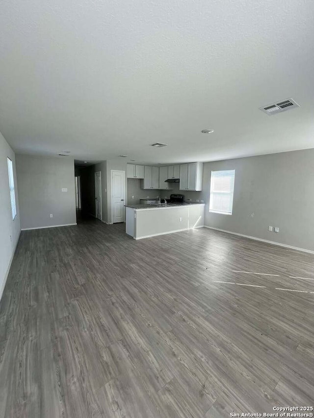 unfurnished living room featuring hardwood / wood-style flooring and a textured ceiling