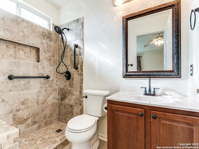 bathroom with vanity, ceiling fan, toilet, and a tile shower