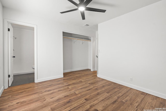 unfurnished bedroom with a closet, ensuite bath, ceiling fan, and dark wood-type flooring