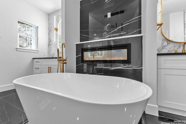 bathroom featuring a multi sided fireplace, a bathtub, and vanity