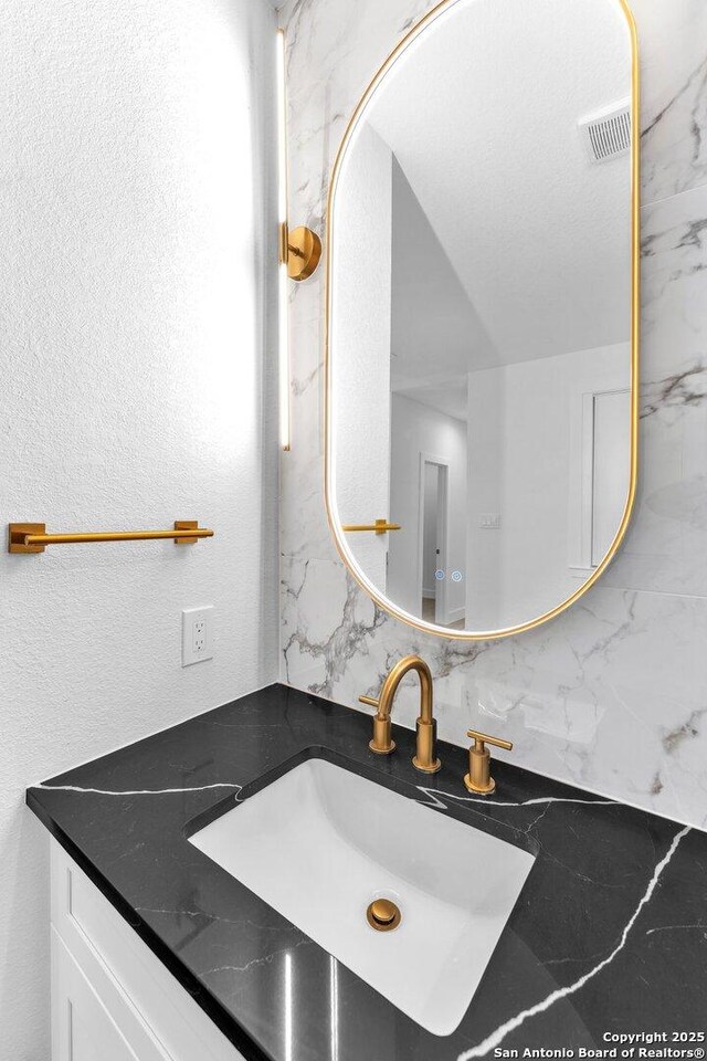 bathroom with decorative backsplash, vanity, and a textured ceiling