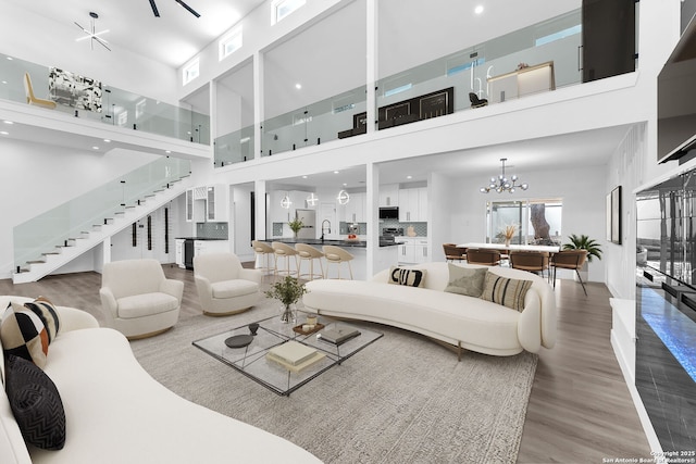 living room featuring hardwood / wood-style floors, a towering ceiling, sink, and an inviting chandelier