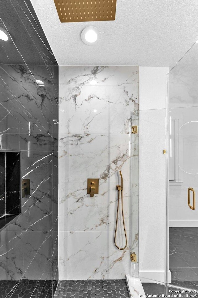 bathroom featuring a shower with shower door and a textured ceiling