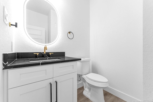 bathroom with hardwood / wood-style flooring, vanity, and toilet