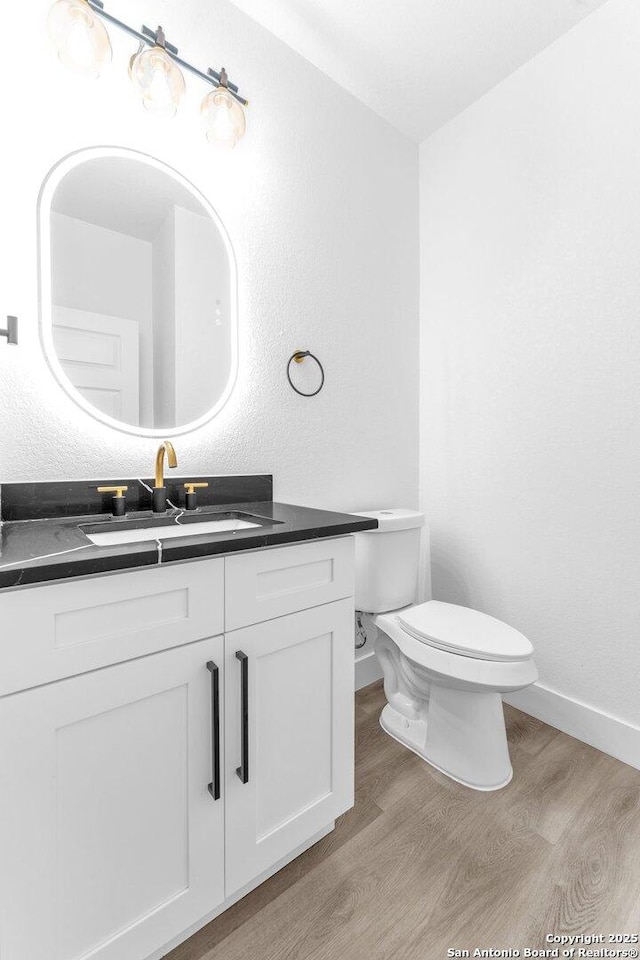 bathroom featuring wood-type flooring, vanity, and toilet