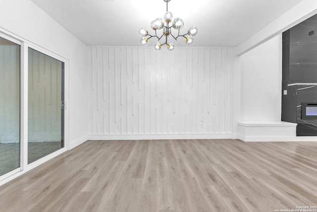 interior space with light wood-type flooring, wooden walls, and a chandelier