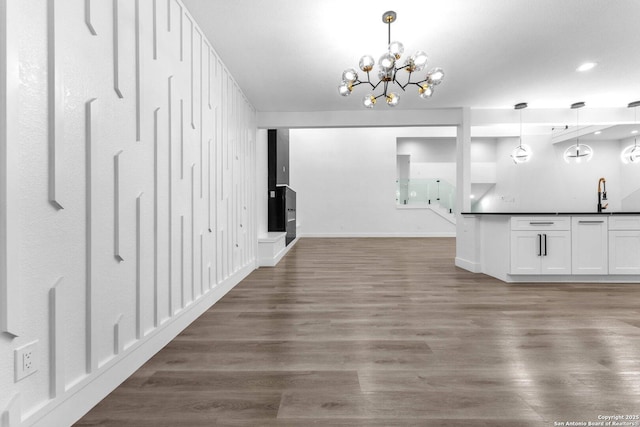 interior space with sink, decorative light fixtures, a chandelier, white cabinets, and dark hardwood / wood-style floors