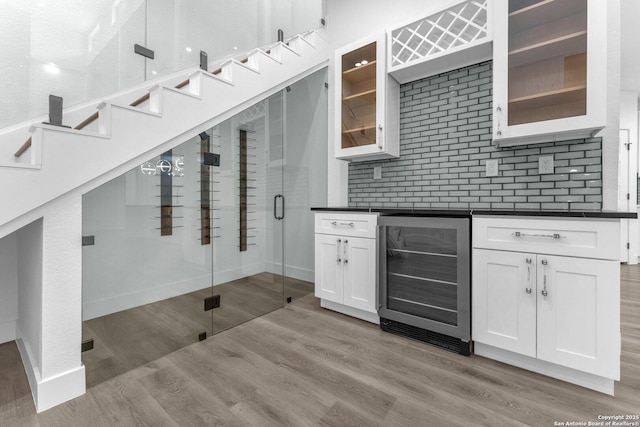 kitchen with backsplash, wine cooler, white cabinetry, and light hardwood / wood-style floors