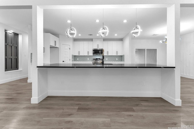 kitchen with kitchen peninsula, tasteful backsplash, stainless steel appliances, pendant lighting, and white cabinetry