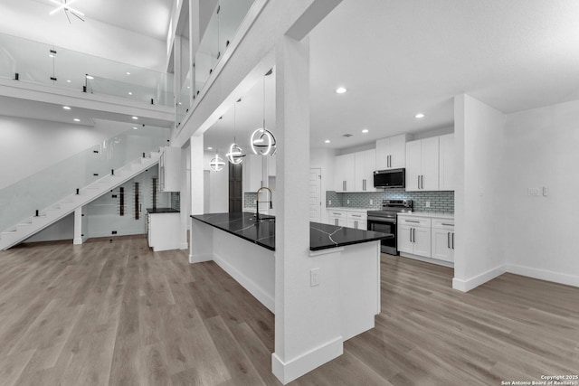 kitchen with kitchen peninsula, stainless steel appliances, decorative light fixtures, white cabinets, and light hardwood / wood-style floors