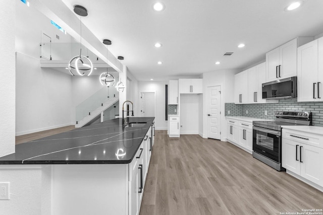 kitchen with hanging light fixtures, white cabinets, stainless steel appliances, and sink