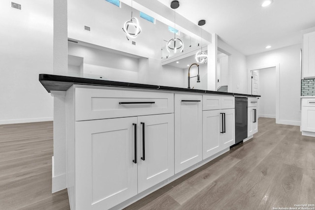 kitchen with white cabinetry, dishwasher, tasteful backsplash, decorative light fixtures, and light wood-type flooring