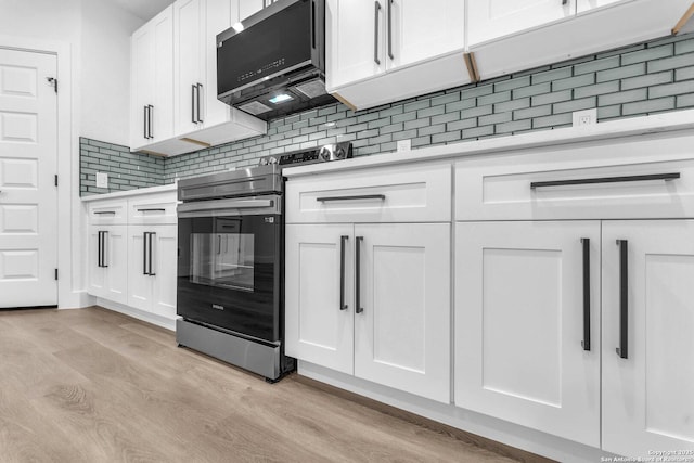 kitchen with tasteful backsplash, white cabinetry, light wood-type flooring, and range