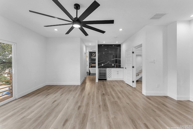 unfurnished living room featuring wine cooler, ceiling fan, and light hardwood / wood-style flooring