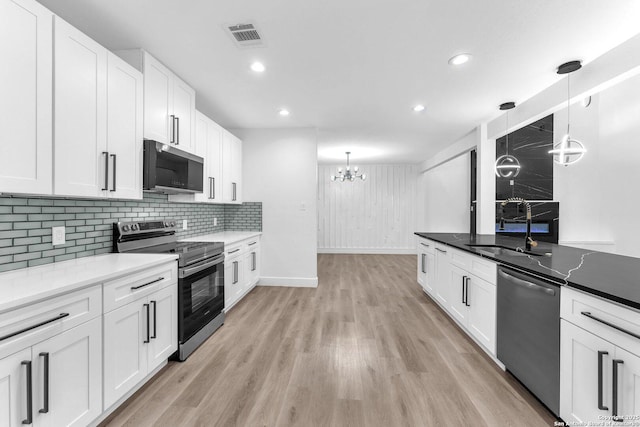 kitchen with white cabinets, sink, hanging light fixtures, and appliances with stainless steel finishes