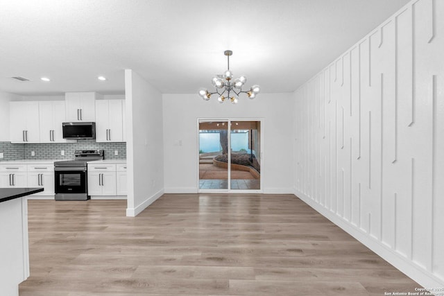 kitchen featuring hanging light fixtures, an inviting chandelier, backsplash, white cabinets, and appliances with stainless steel finishes