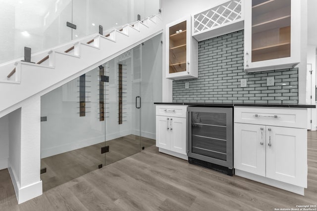 kitchen featuring white cabinets, decorative backsplash, light hardwood / wood-style flooring, and wine cooler