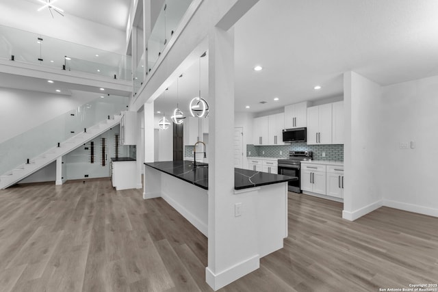 kitchen with white cabinetry, kitchen peninsula, light hardwood / wood-style floors, decorative light fixtures, and appliances with stainless steel finishes