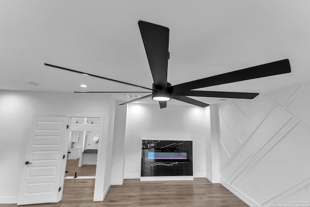 interior details featuring ceiling fan, wood-type flooring, and a fireplace