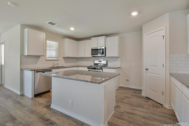 kitchen with white cabinetry, a center island, sink, stainless steel appliances, and wood-type flooring