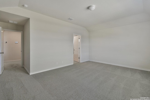 carpeted spare room with vaulted ceiling