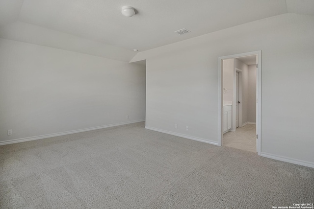 carpeted spare room with vaulted ceiling