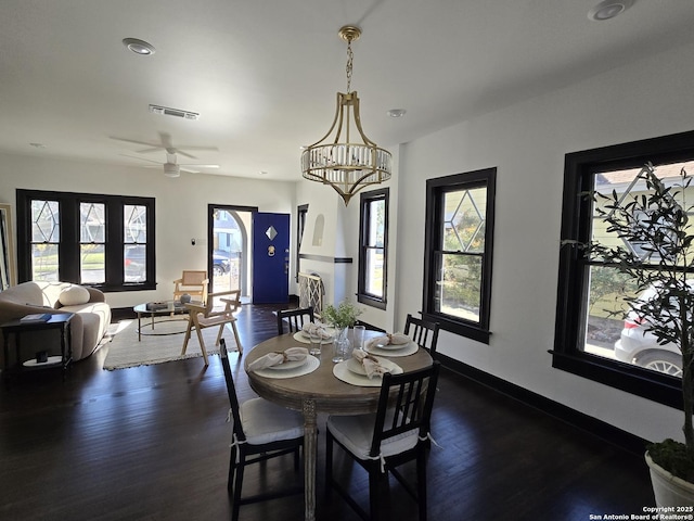 dining area featuring ceiling fan with notable chandelier and dark hardwood / wood-style floors