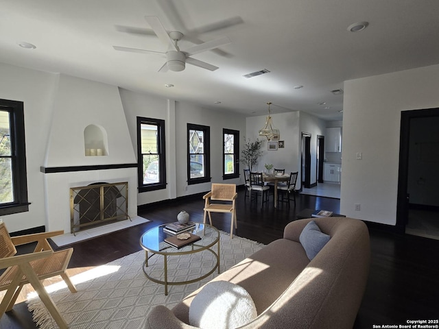 living room featuring ceiling fan, a large fireplace, and hardwood / wood-style flooring