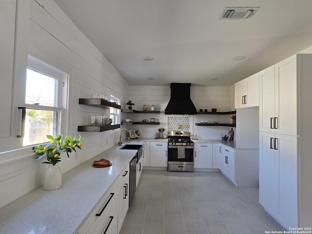 kitchen with premium range hood, light stone counters, stainless steel appliances, sink, and white cabinets