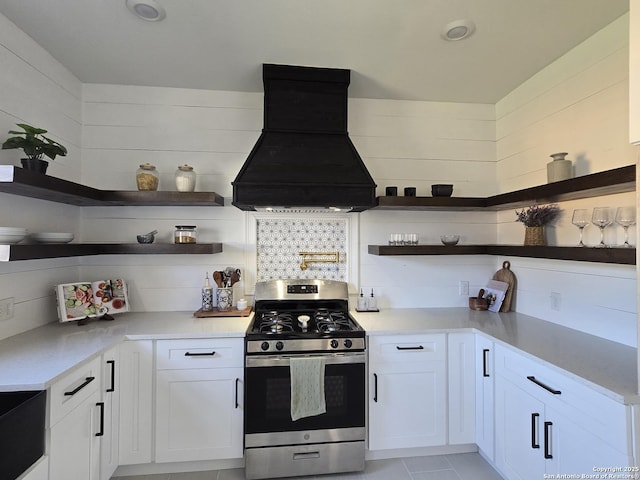 kitchen featuring white cabinets, gas range, backsplash, and premium range hood