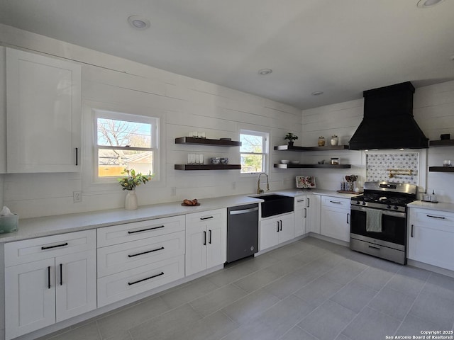 kitchen featuring decorative backsplash, appliances with stainless steel finishes, custom range hood, sink, and white cabinets