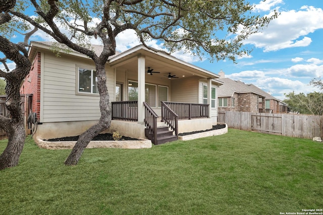 back of property with a lawn, ceiling fan, and covered porch