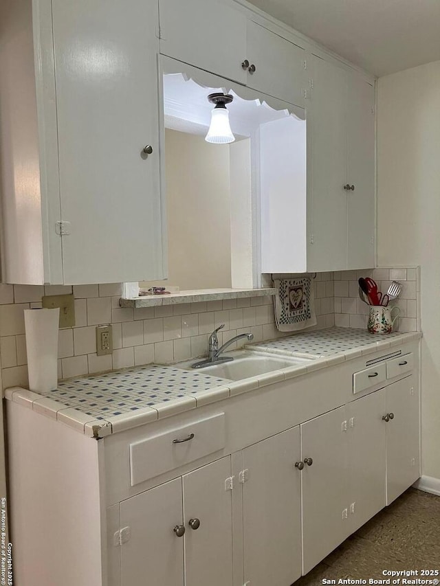 kitchen with decorative backsplash, sink, white cabinets, and tile counters