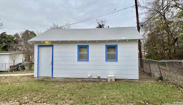 back of property featuring a lawn and an outdoor structure