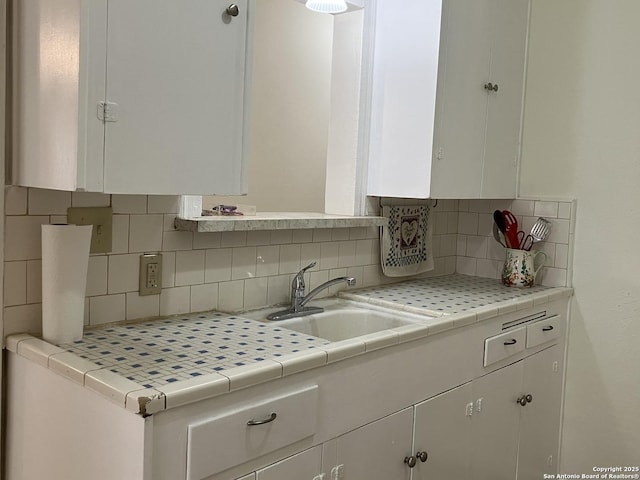 kitchen with tile countertops, decorative backsplash, sink, and white cabinets